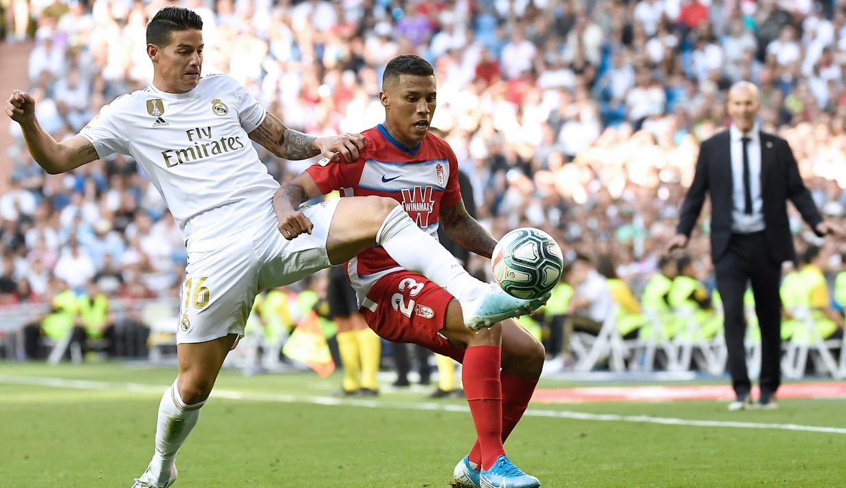 Gelandang Real Madrid, James Rodriguez, berebut bola dengan striker Granada, Darwin Machis, pada laga La Liga Spanyol di Stadion Santiago Bernabeu, Madrid, Sabtu (5/10). Madrid menang 4-2 atas Granada. (AFP/Pierre-Philippe Marcou)