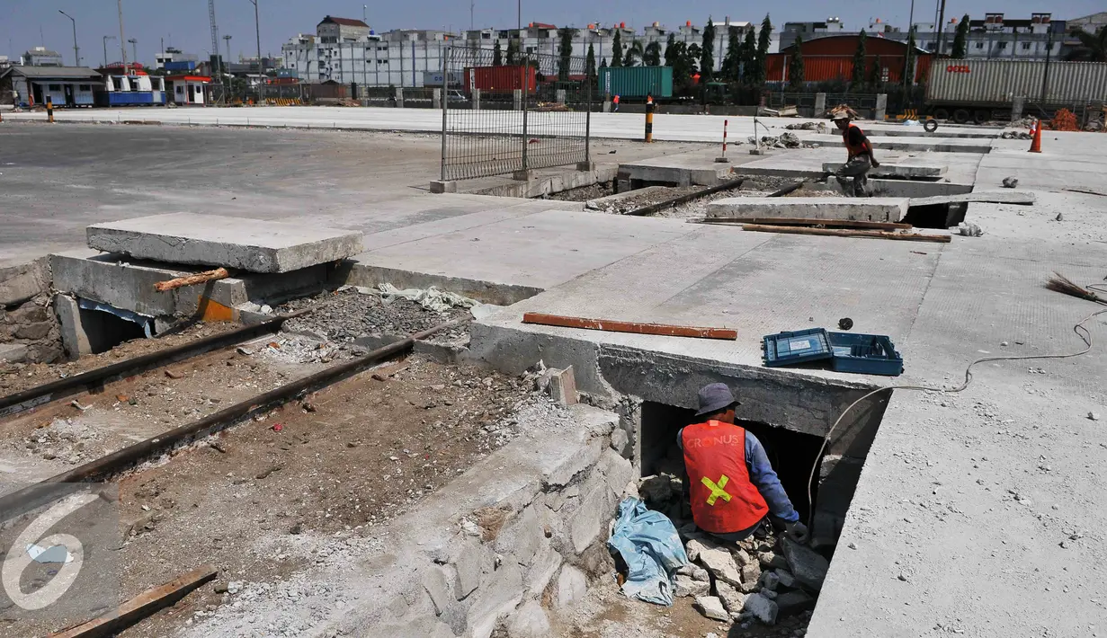 Pekerja membongkar rel kereta yang tertutup beton di Pelabuhan Tanjung Priok, Jakarta, Jumat (11/9/2015). Jalur kereta yang dibangun sejak zaman Belanda tersebut aktif bisa membantu keluar masuk barang di pelabuhan. (Liputan6.com/Gempur M Surya)