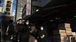 Orang-orang berjalan melalui jalan di area "pasar ikan luar" Tsukiji di Tokyo pada 28 Desember 2022. Menjelang liburan Tahun Bar, turis asing dan penduduk lokal berkunjung  ke pasar itu untuk menikmati hidangan bermacam makanan laut. (AFP/Richard A. Brooks)