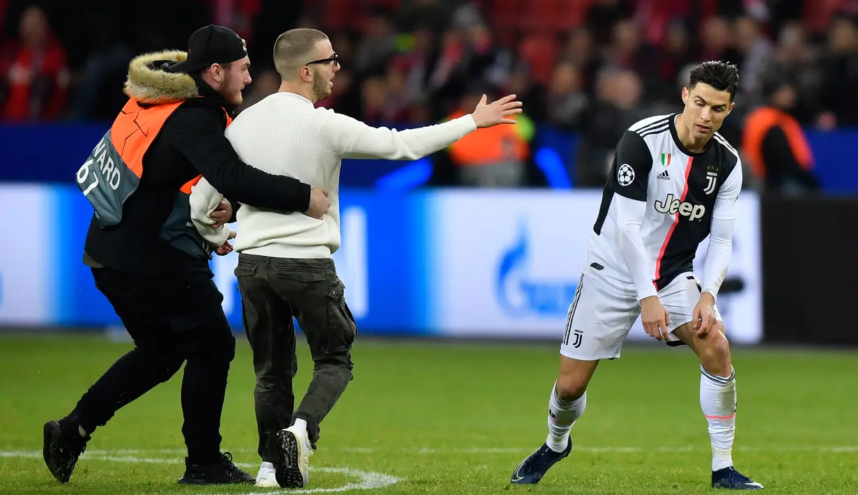 Seorang penyusup dievakuasi saat masuk ke lapangan untuk memeluk Cristiano Ronaldo pada laga Liga Champions antara Juventus melawan Bayer Leverkusen di Bay Arena, Leverkusen, Jerman, Rabu (11/12/2019). (AP Photo/Martin Meissner)