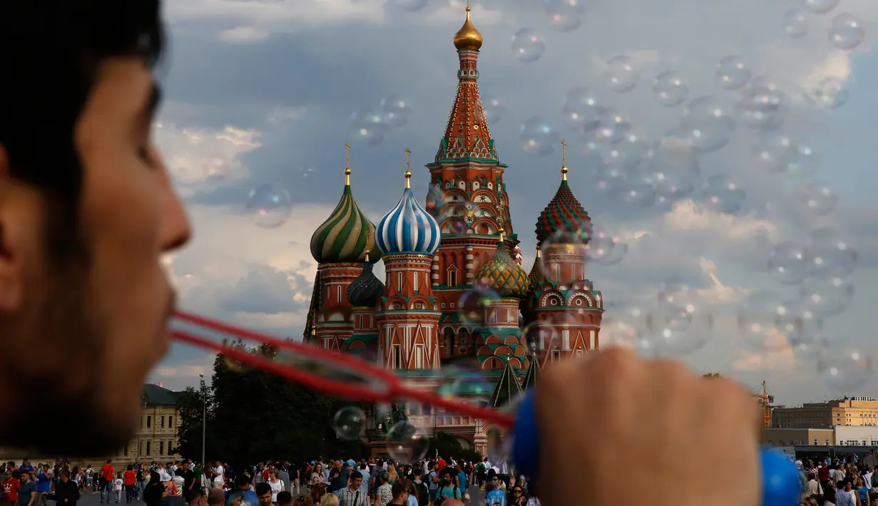 Seorang pria meniup gelembung di Lapangan Merah jelang final Piala Dunia 2018 antara Prancis melawan Kroasia di Moskow, Rusia, (13/7).  (AP Photo/Rebecca Blackwell)