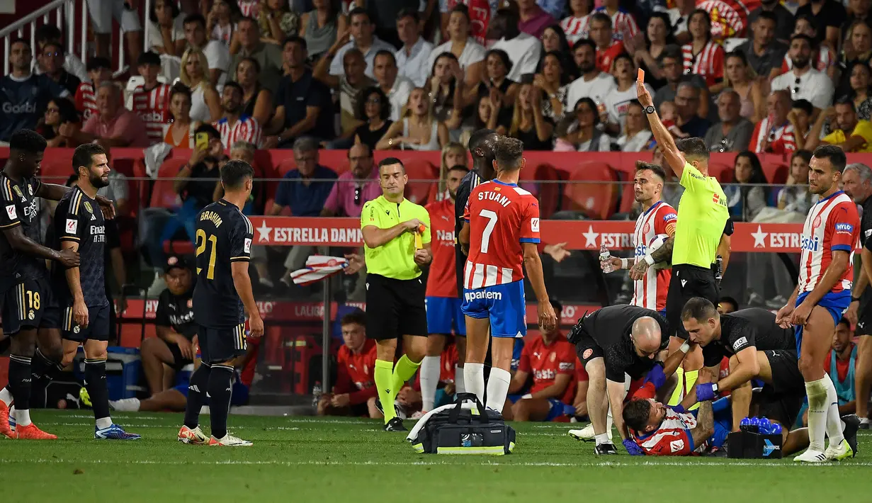 Wasit Juan Luis Pulido Santana memberikan kartu merah kepada bek Real Madrid, Nacho (kedua kiri) setelah melakukan pelanggaran keras terhadap striker Girona, Portu (bawah) pada laga pekan ke-8 Liga Spanyol 2023/2024 di Montilivi Stadium, Girona, Spanyol, Sabtu (30/9/2023) malam WIB. (AFP/Josep Lago)