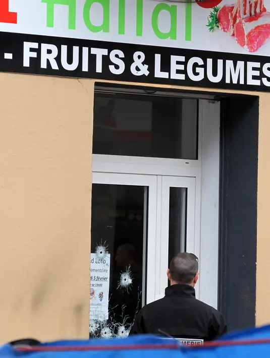 Seorang polisi berdiri di depan toko daging halal yang diberondong peluru di Propriano, di pulau Corsica, Prancis, Rabu (3/2). Tembakan membuat kaca dan jendela toko milik warga muslim itu mengalami kerusakan. (PASCAL POCHARD-CASABIANCA/AFP)