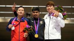 Peraih medali emas Muhammad Sejahtera Dwi Putra dari Indonesia (tengah) berpose dengan peraih medali perak Huu Vuong Ngo dari Vietnam, kiri, dan peraih medali perunggu Youjin Jeong dari Korea Selatan dalam upacara penghargaan cabang olahraga menembak nomor 10 meter lari jarak jauh putra di Fuyang Yinhu Sports Centre pada Asian Games ke-19 di Hangzhou, China, Senin, 25 September 2023. (AP Photo/Aijaz Rahi)