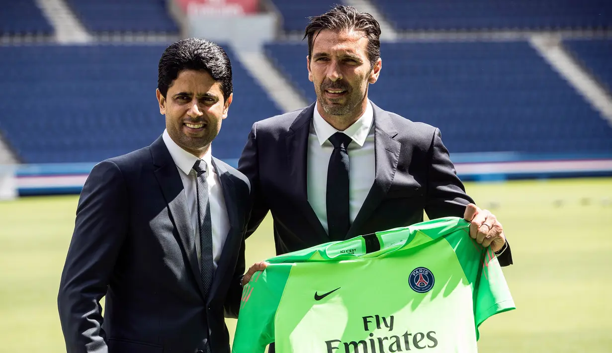 Kiper anyar PSG, Gianluigi Buffon berpose bersama Ketua klub dan CEO Paris Saint-Germain, Nasser Al Khelaifi sambil memegang jersey PSG saat resmi diperkenalkan sebagai pemain baru di stadion Parc des Princes, Paris, Senin (9/7). (AP/Jean-Francois Badias)