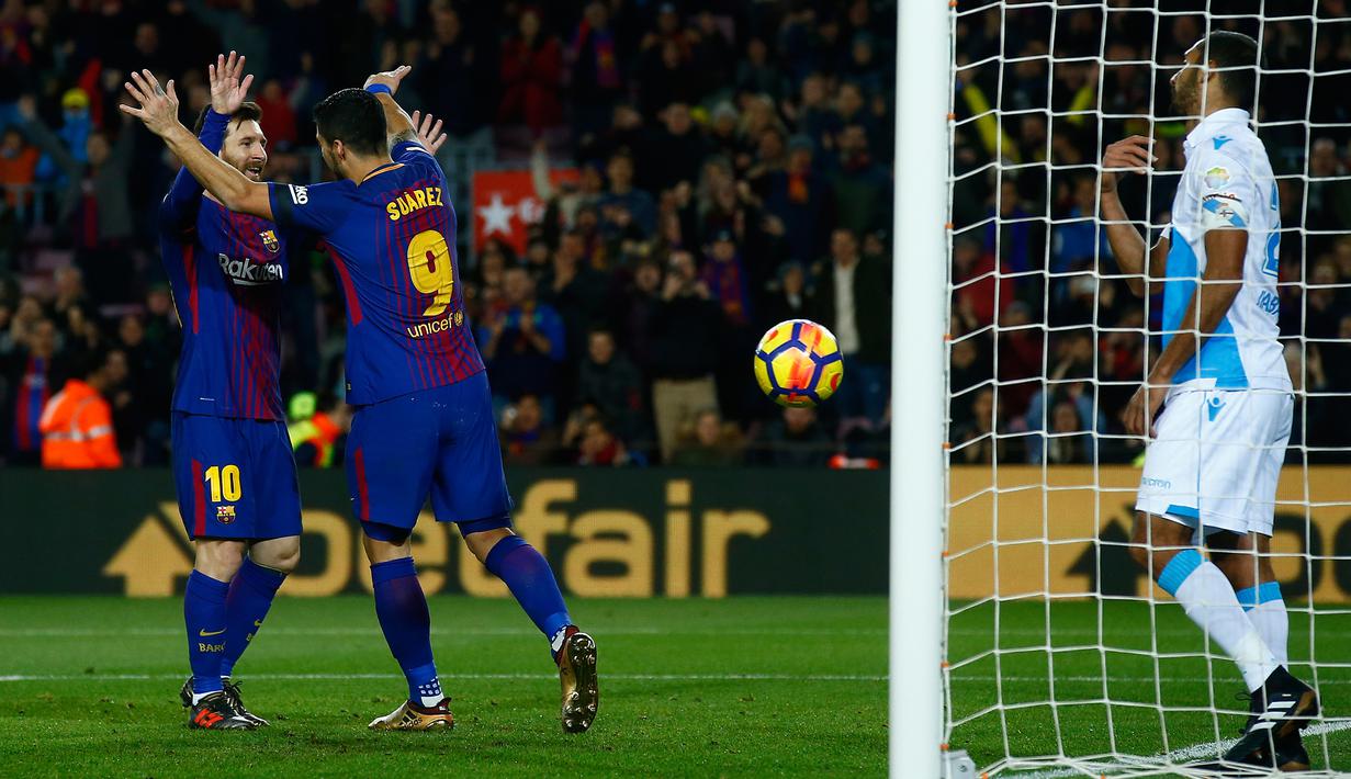 Pemain Barcelona, Lionel Messi merayakan gol rekan setimnya, Luis Suarez ke gawang Deportivo La Coruna pada pertandingan pekan ke-16 La Liga di Stadion Camp Nou, Senin (18/12). Barcelona unggul 4-0 lewat dua gol Suarez.  (AP/Manu Fernandez)