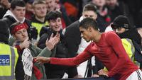 Pemain Manchester United, Raphael Varane, memberikan jersey kepada fans setelah laga Leeds United pada laga Liga Inggris di Stadion Old Trafford, Rabu (8/2/2023). Hasil imbang ini membuat MU tertahan di peringkat ke-3 dengan 43 poin, gagal menyamai poin Man City yang ada satu strip di atas dengan 45 poin. Bagi Leeds, hasil ini cukup untuk mengangkat mereka ke posisi 16 dengan 19 poin. (AFP/Oli Scarff)