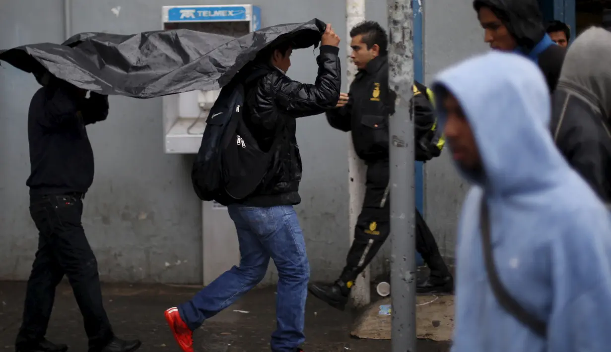 Warga Meksiko melindungi diri dari hujan di luar stasiun bus di Guadalajara, Jumat (23/10). Badai Patricia, salah satu badai terkuat sepanjang sejarah, menyerang pantai pasifik Meksiko.  (REUTERS/Edgard Garrido)