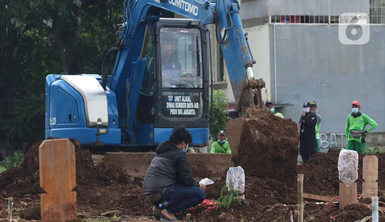 Aktivitas alat berat jenis eksavator membantu proses penggalian makam jenazah dengan protokol COVID-19 di area khusus TPU Srengseng Sawah, Jakarta, Kamis (14/1/2021). Pada Selasa (12/1) lalu, 47 jenazah dimakamkan dengan protokol COVID-19 di TPU Srengseng Sawah. (Liputan6.com/Helmi Fithriansyah)