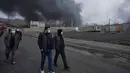 Media lokal Iran melaporkan kebakaran besar terjadi di Teheran dan mengonfirmasi bahwa kilang minyak dan fasilitas penyimpanan minyak terkena dua rudal serangan udara. Tampak dalam foto, empat pria berjalan berlatar kepulan asap tebal dari serangan gabungan AS-Israel terhadap fasilitas penyimpanan minyak pada Sabtu 7 Maret 2026 malam yang membubung ke langit di Teheran, Minggu, 8 Maret 2026. (AP Photo/Vahid Salemi)