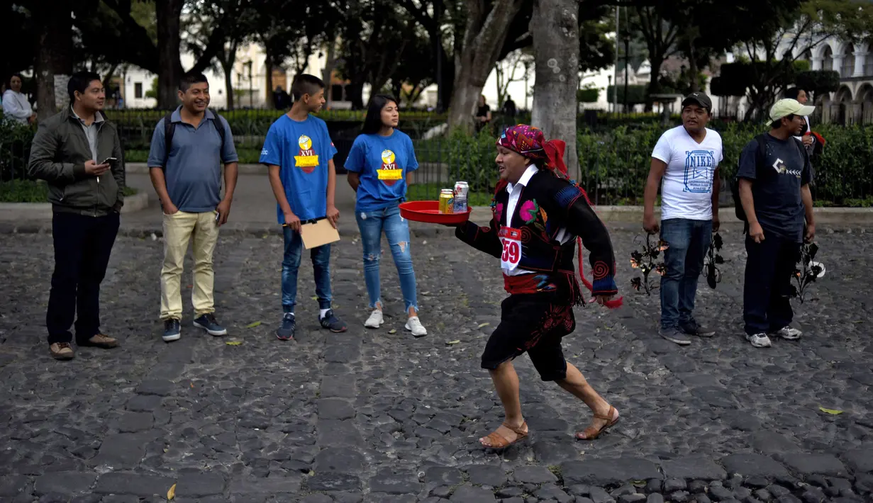 Seorang pramusaji beradu kecepatan sambil membawa nampan dalam Waiters Race ke-16 di Antigua, barat daya Ibu Kota Guatemala City, Rabu (14/11). Lomba ini diikuti oleh ratusan peserta yang merupakan pelayan restoran dan kafe setempat. (JOHAN ORDONEZ/AFP)