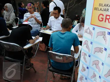 Pelatih mengajarkan bahasa isyarat saat aksi sosialisasi di Car Free Day (CFD), Jakarta, Minggu (11/9). Sosialisasi belajar bahasa isyarat untuk mengkampanyekan penggunaan bahasa isyarat dalam dialog para penyandang tuna rungu (Liputan6.com/Faizal Fanani)