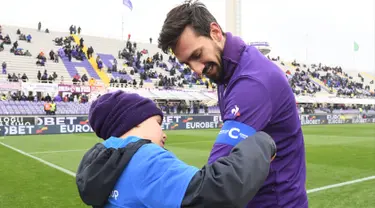 Foto pada tanggal 25 Februari 2018, seorang anak laki-laki memberi ban kapten kepada pemain Fiorentina, Davide Astori sebelum pertandingan Liga Italia di Florence. Davide Astori meninggal pada usia 31 tahun. (AFP Photo/Claudio Giovannini)