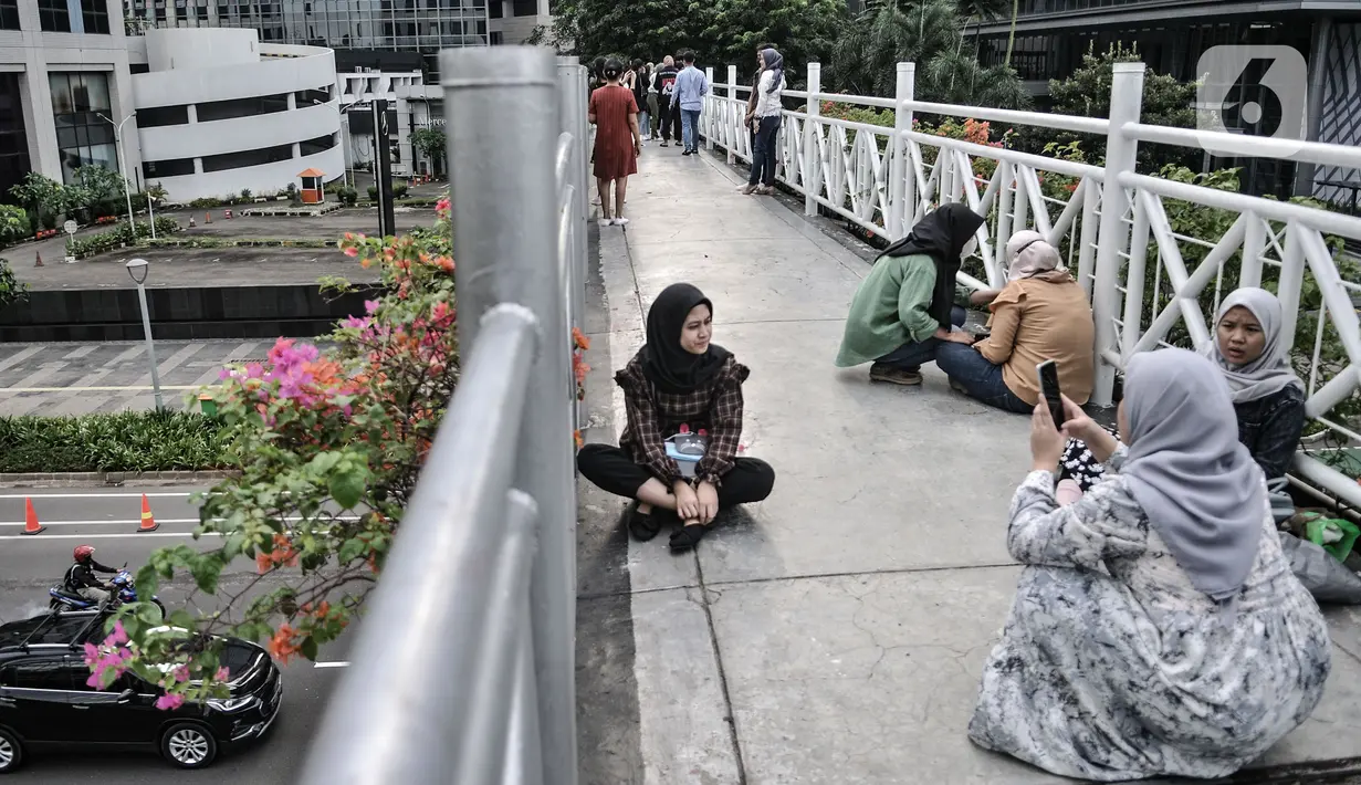 Warga berfoto dengan latar belakang gedung perkantoran di jembatan penyeberangan orang (JPO) tanpa atap di kawasan Sudirman, Jakarta, Minggu (4/4/2021). JPO tanpa atap masih menjadi wisata alternatif warga ibu kota menghabiskan waktu akhir pekan untuk berfoto-foto. (merdeka.com/Iqbal S Nugorho)