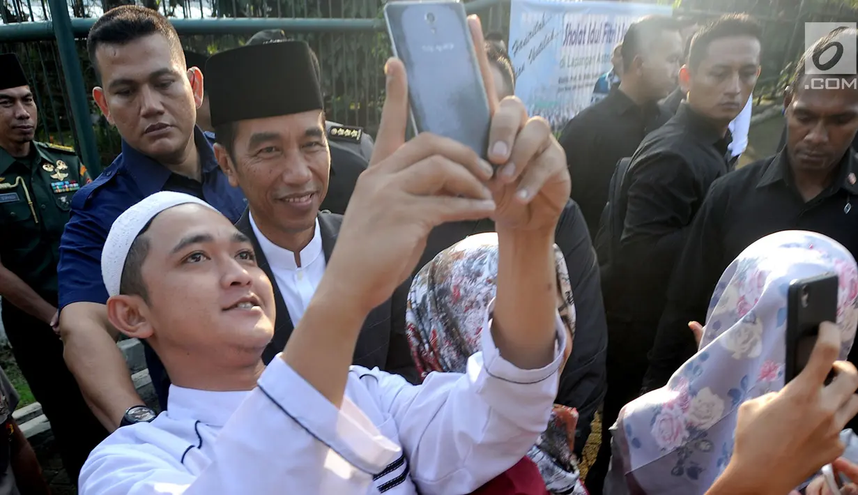 Seorang warga berselfie dengan Presiden Joko Widodo usai melaksanakan salat id Hari Raya Idul Fitri 1 Syawal 1439 H di Lapangan Astrid, Kebun Raya Bogor, Jumat (15/6). (Merdeka.com/Arie Basuki)