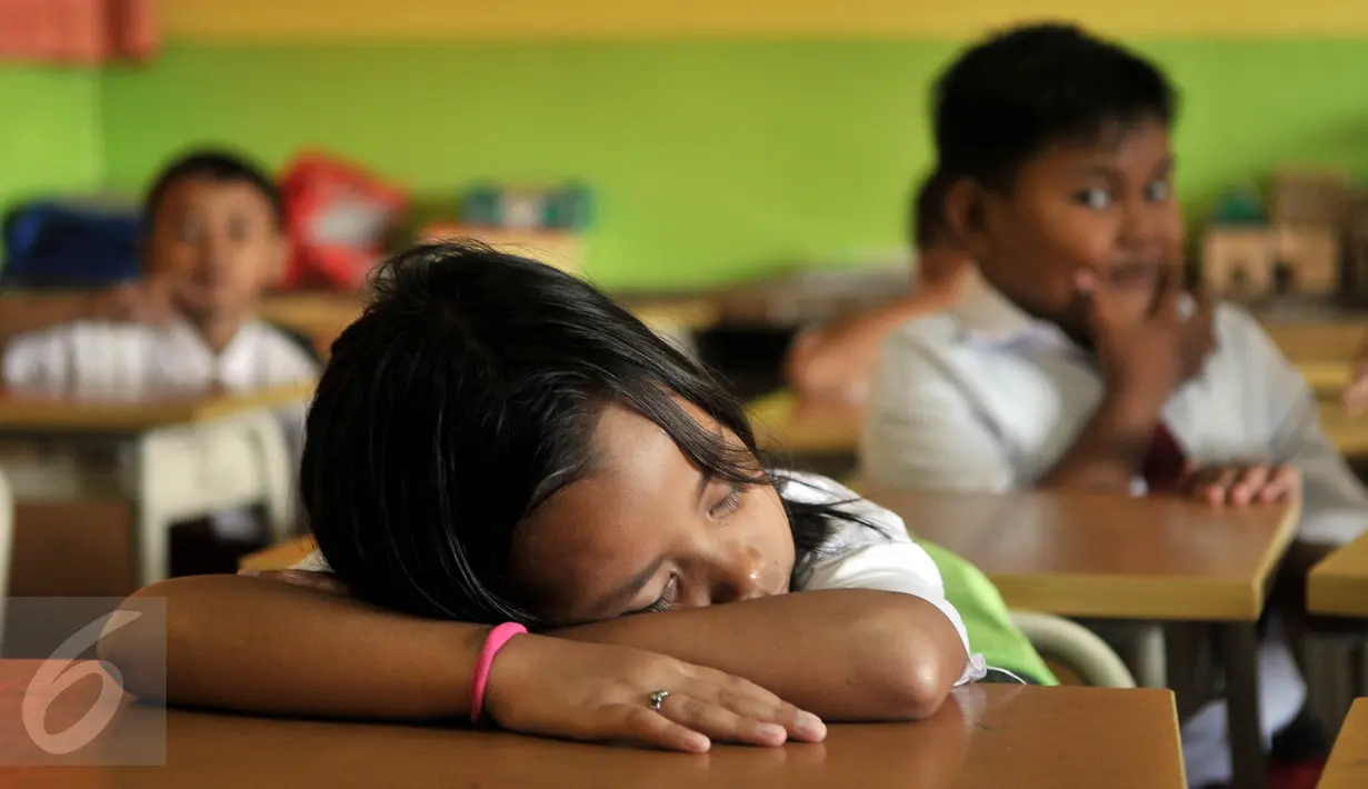Seorang siswi tertidur di kelas usai mengikuti upacara di SDN Manggarai 17 Pagi, Jakarta, Senin (18/7). Hari pertama sekolah diisi dengan kegiatan halalbilahal dan pengenalan siswa dan orang tua dengan lingkungan pendidikan. (Liputan6.com/Johan Tallo)