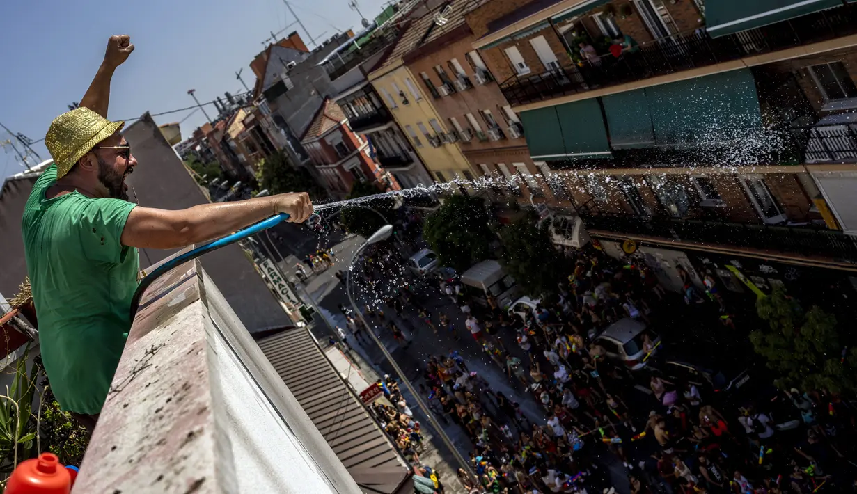 Seorang pria menyemprotkan air menggunakan selang saat perang air tahunan di jalan-jalan lingkungan Vallecas, Madrid, Spanyol, 17 Juli 2022. Selain warga sekitar, acara ini juga diikuti orang-orang dari daerah lain di Madrid bahkan turis asing. (AP Photo/Manu Fernandez)