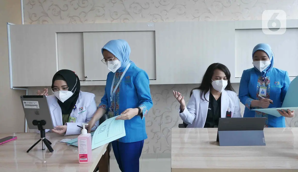 Dokter Spesialis Onkologi Radiasi, Ade Margaretha (kedua kanan) bersama Dokter Umum Indria Febriani (kiri) saat memberikan pelayanan medis jarak jauh atau Telemedicine pada pasien umum di Rumah Sakit Umum Daerah (RSUD) Pasar Minggu, Jakarta, Jumat (18/2/2022). (Liputan6.com/Herman Zakharia)