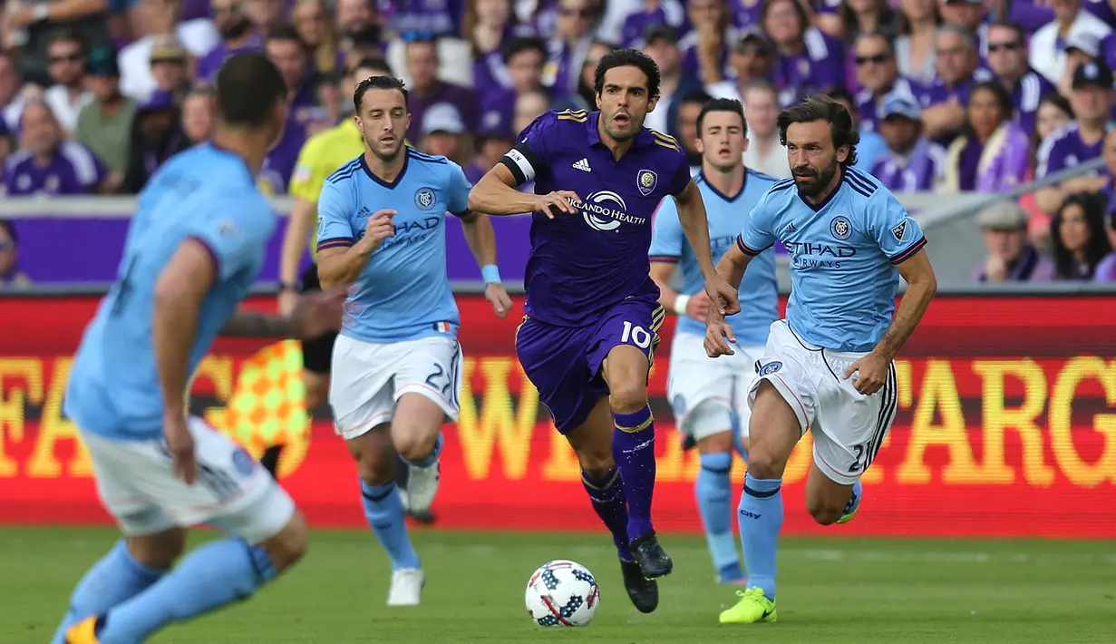 Pemain Orlando City SC, Ricardo Kaka (tengah) berusaha melewati pemain New York City FC, Andrea Pirlo (kanan) dan rekan-rekannya saat laga lanjutan MLS di Orlando City Stadium, Orladndo, Florida, 5 Maret 2017. Kaka tercatat telah mencetak 24 gol dan membuat 19 assist dalam 79 pertandingan sebelum gantung sepatu pada 2017. Sementara Pirlo telah mengemas 1 gol dan 9 assist dalam 62 penampilannya sebelum pensiun pada 2018. (AFP/Getty Images/Alex Menendez)