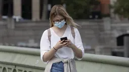 Seorang wanita yang mengenakan masker berjalan di Jembatan Westminster di London, Inggris (8/9/2020). Warga Inggris didesak untuk menangani pandemi dengan serius atau menghadapi "jalan bergelombang" di masa yang akan datang. (Xinhua/Han Yan)