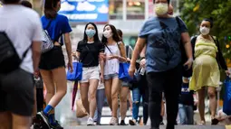 Dua wanita mengenakan masker sebagai tindakan pencegahan Covid-19 saat berjalan di Hong Kong (13/5/2020). Dua orang di Hong Kong dinyatakan positif Covid-19, mengakhiri perjalanan 24 hari tanpa kasus baru yang mulai melonggarkan peraturan jarak sosial. (AFP/Anthony Wallace)