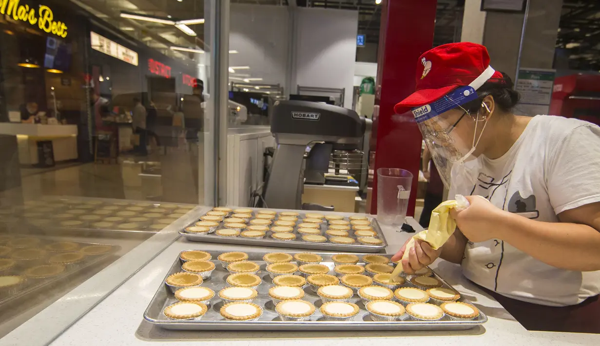 Seorang staf toko kue yang mengenakan pelindung wajah membuat kue tart telur (egg tart) di Square One Shopping Center di Mississauga, Ontario, Kanada  (9/10/2020). Tingkat pengangguran di Kanada pada September turun menjadi 9 persen dari 10,2 persen pada Agustus. (Xinhua/Zou Zheng)