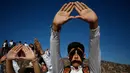 Pengunjung mengangkat tangan mereka yang membentuk segitiga saat merayakan equinox musim semi di situs arkeologi Teotihuacan, Meksiko (21/3). Tradisi Equinox ditandai dengan posisi matahari yang bersinar vertikal. (AP Photo/Rebecca Blackwell)