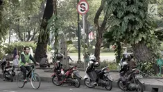 Pengendara sepeda melintas di samping deretan sepeda motor yang terparkir di sekitar Taman Suropati, Jakarta, Selasa (28/8). Meski terpampang rambu larangan parkir dan berhenti, pengendara tetap parkir di sekitar taman. (Liputan6.com/Immanuel Antonius)