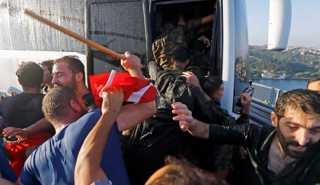 Seorang polisi melindungi tentara dari amukan warga Turki di Jembatan Bosphorus, Istanbul , Turki, (16/7).Tentara berebutan masuk kedalam bus untuk menyelamatkan diri dari pukulan warga. (REUTERS / Murad Sezer)