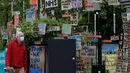 Seorang pria berjalan melewati kumpulan plakat yang dirancang oleh seniman lokal Peter Liversidge untuk mendukung Layanan Kesehatan Nasional (National Health Service/NHS) di London, Inggris, (29/4/2020). (Xinhua/Han Yan)