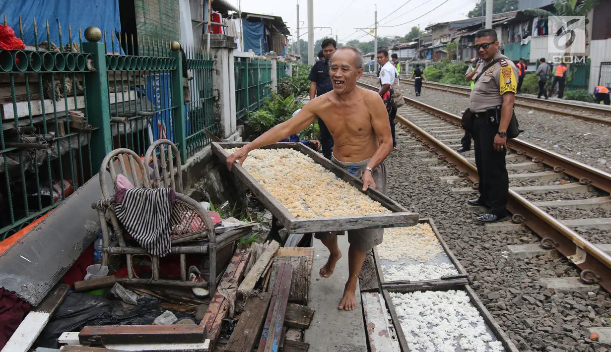 Seorang warga sekitar menyikirkan barang miliknya saat dilakukan penertiban lapak dan bangunan liar di sepanjang jalur kereta di kawasan Grogol, Jakarta Barat, Kamis (22/2). (Liputan6.com/Arya Manggala)