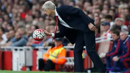 Pelatih Arsenal Arsene Wenger memungut bola pada Laga lanjutan Liga Premier Inggris di Emirates Stadium. Minggu (04/10/2015). Arsenal menang 3-0 atas MU. (Action Images via Reuters / Carl Recine Livepic)