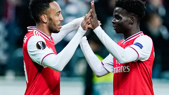 Penyerang Arsenal, Bukayo Saka (kanan) mendapat ucapan selamat dari Pierre-Emerick Aubameyang, setelah mencetak gol ke gawang Eintracht Frankfurt, di Frankfurt am Main, Jumat (20/9/2019) dini hari WIB. (AFP / Uwe Anspach)