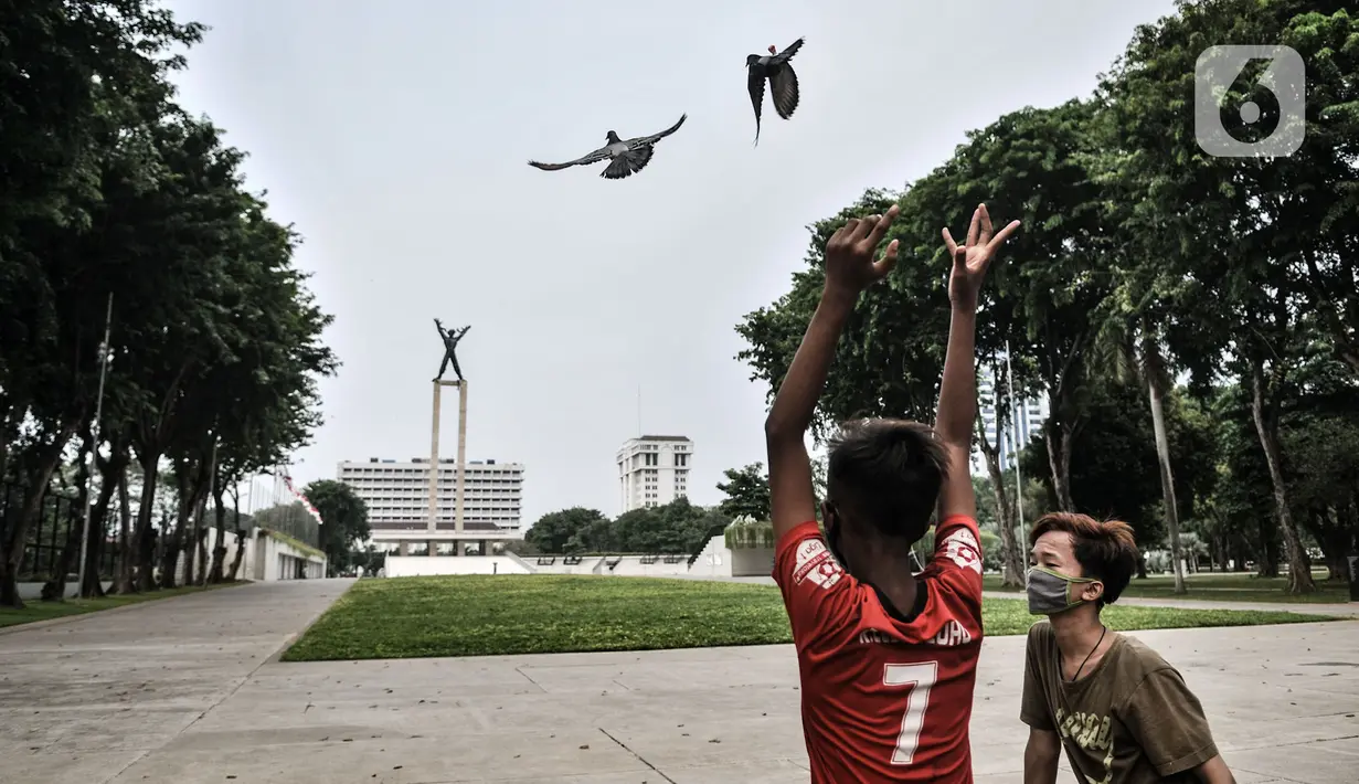 Anak-anak bermain burung dara di depan Lapangan Banteng, Jakarta, Kamis (15/9/2020). Lapangan Banteng dan hutan kota di Ibu Kota Kembali ditutup sementara saat penerapan pembatasan sosial berskala besar (PSBB) Jakarta guna menekan penyebaran Covid-19 di ruang publik. (merdeka.com/Iqbal Nugroho)