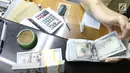 Pekerja menghitung mata uang Dolar AS di jasa penukaran uang asing di Jakarta, Rabu (19/6/2019). Nilai tukar rupiah terhadap Dolar AS sore ini Rabu (19/6) ditutup menguat sebesar Rp 14.269 per dolar AS atau menguat 56,0 poin (0,39 persen) dari penutupan sebelumnya. (Liputan6.com/Angga Yuniar)