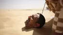 Seorang pria dikubur dengan pasir gurun di Siwa, Mesir, 12 Agustus 2015. Terapi menguburkan diri di dalam pasir gurun saat terik matahari ini diyakini dapat menyembuhkan rematik, sakit sendi, dan impotensi seksual. (REUTERS/Asmaa Waguih)