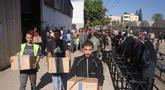 Warga Palestina mengangkat kotak bantuan dari Program Pangan Dunia (WFP) di pusat distribusi di desa Al-Zawayda, di tengah-tengah Jalur Gaza, pada 27 Oktober 2025. (BASHAR TALEB/AFP)