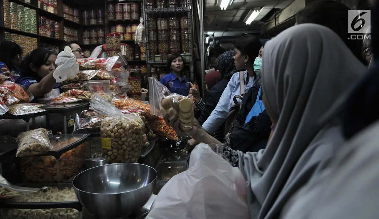 Pedagang kue kering melayani pembeli di Pasar Jatinegara, Jakarta, Selasa (5/6). Menjelang Lebaran, sudah menjadi tradisi masyarakat berbondong-bondong membeli kebutuhan Lebaran seperti pakaian, kue kering dan lain-lain. (Merdeka.com/ Iqbal S. Nugroho)