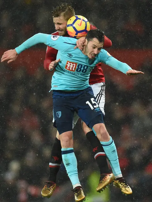 Bek AFC Bournemouth, Adam Smith melompat untuk merebut bola dari pemain Manchester United, Luke Shaw pada lanjutan laga Premier League di Old Trafford, Rabu (13/12). Manchester United unggul hanya 1-0 lewat gol Romelu Lukaku. (Oli SCARFF / AFP)