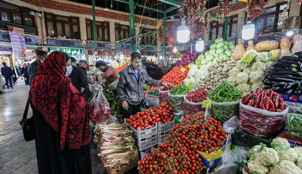 Seorang pembeli mengenakan masker dan sarung tangan lateks, karena pandemi virus corona COVID-19, membeli sayuran selama bulan suci Ramadan di Taheran, Iran (25/4/2020). (AFP/Atta Kenare)