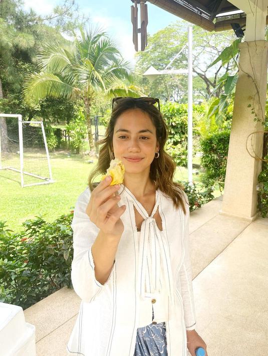 Rambutnya yang pirang dibiarkan terurai dengan menambahkan kacamata hitam yang disangkutkan di atas kepalanya. Pevita berpose sambil melihat buah durian yang pertama kali ia makan. (Instagram/pevpearce)