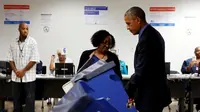 Pekerja membantu Presiden AS Barack Obama ketika akan memberikan suaranya di mesin voting elektronik di TPS awal di pusat kota Chicago, Jumat (7/10). Obama memberikan suaranya lebih awal untuk Pilpres AS pada 8 November 2016. (REUTERS/Jonathan Ernst)