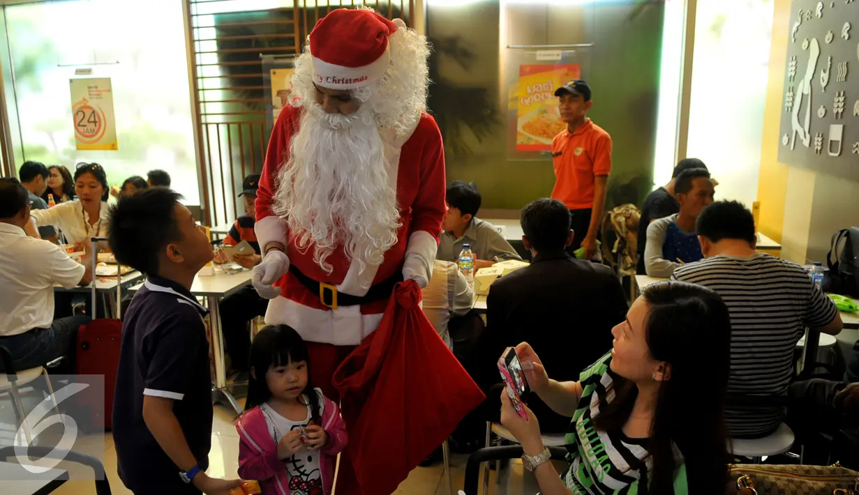 Santa Claus berbincang dengan anak-anak di Bandara Soekarno Hatta, Tangerang, Banten, Selasa (22/12). Sejumlah orang berkostum santa claus membagikan coklat kepada penumpang yang berada dibandara. (Liputan6.com/Faisal R Syam)