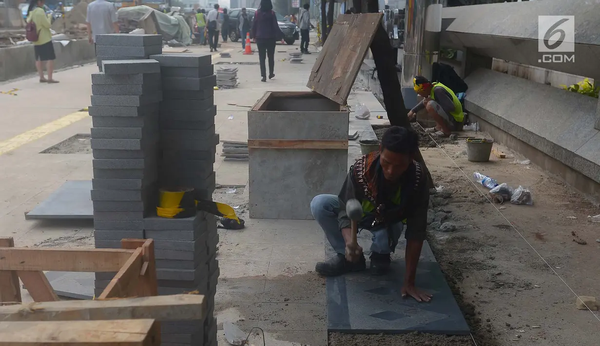Pekerja menyelesaikan penataan jalur pedestrian di sepanjang Jalan Jenderal Sudirman - Jalan MH Thamrin, Jakarta, Selasa (10/7). Gubernur DKI Anies Baswedan menyatakan pelebaran trotoar itu  akan rampung Juli ini. (Merdeka.com/Imam Buhori)