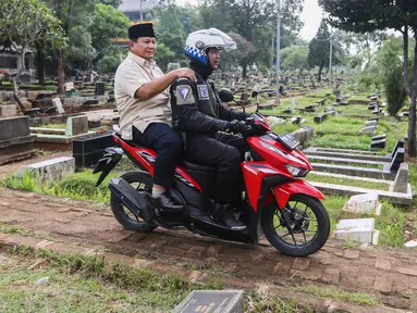 Calon Presiden nomor urut 2 Prabowo Subianto (belakang) dibonceng sepeda motor menuju makam ayahnya Soemitro Djojohadikusumo di Tempat Pemakaman Umum (TPU) Karet Bivak, Jakarta, Kamis (15/2/2024). (Liputan6.com/Angga Yuniar)