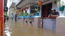 Warga bermain ponsel saat banjir merendam RW 06 kawasan Mekarsari, Depok, Jawa Barat, Sabtu (20/2/2021). Banjir yang disebabkan meluapnya aliran Kali Cipinang Timur ini terjadi akibat intensitas hujan tinggi di wilayah tersebut (Liputan6.com/Herman Zakharia)