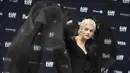 Emma Corrin berpose untuk fotografer di karpet merah pada pemutaran perdana My Policeman di Festival Film Internasional Toronto di Toronto, Ontario (11/9/2022). Emma Corrin juga memasangkan sepasang celana ketat hitam dan jubah panjang. (Photo by Geoff Robins / AFP)