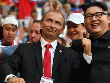 Peniru Presiden Rusia, Vladimir Putin dan pemimpin Korea Utara, Kim Jong-un berpose selama menyaksikan laga penyisihan Grup A Piala Dunia 2018 antara Uruguay vs Rusia di Samara Arena, Senin (25/6). Uruguay berhasil melumat Rusia 3-0. (AFP/EMMANUEL DUNAND)