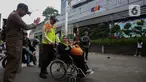 Petugas keamanan KAI Commuter Line membantu seorang calon penumpang lanjut usia (lansia) untuk masuk ke dalam Stasiun Sudirman, Jakarta, Selasa (10/12/2024). (Liputan6.com/Angga Yuniar)