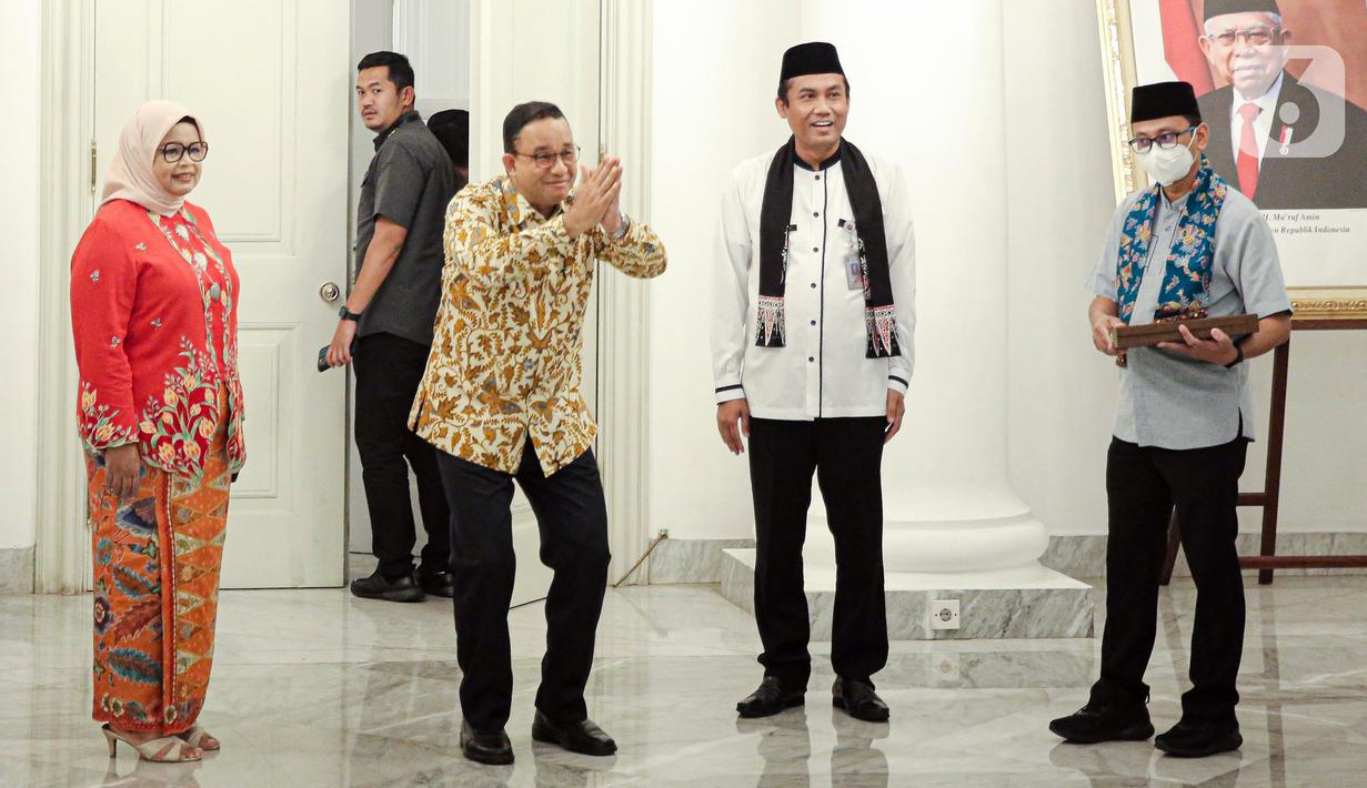 Gubernur DKI Jakarta Anies Baswedan (kedua kiri) ditemani istri Fery Farhati (kiri) memberi isyarat saat menyapa para Aparatur Sipil Negara (ASN) di Balai Kota DKI Jakarta, Jumat (14/10/2022). Di hari terakhir menjabat sebagai Gubernur DKI Jakarta, Anies Baswedan menyempatkan diri untuk menyapa ASN di Balai Kota. (Liputan6.com/Faizal Fanani)